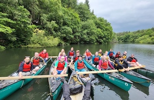 Large group of people in many canoes on a pretty Yorkshire lake